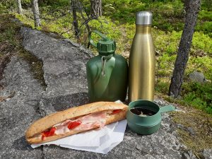 Aamiaistarjoilu Sipoonkorvessa. Täytetty patonki, vesipullo, kahvitermos ja kahvimuki.